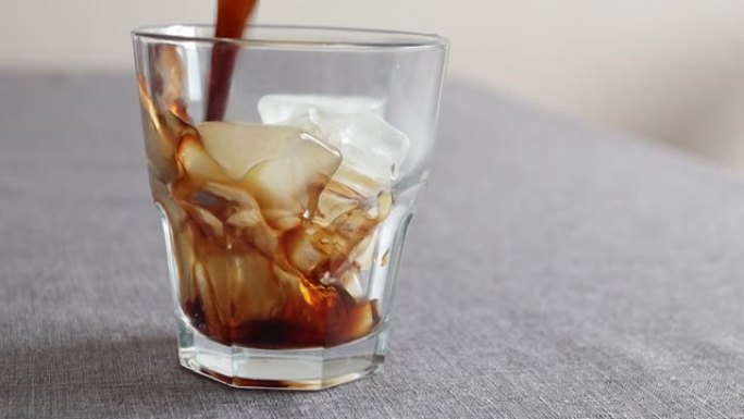 将咖啡倒入玻璃杯冰块中。冰冷咖啡饮料。