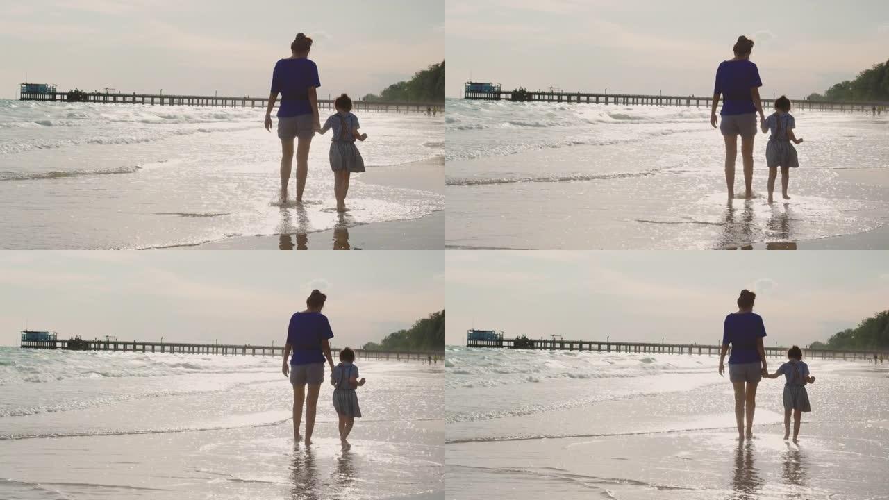剪影4k的母亲和她的孩子女儿光着脚在海边散步和玩耍，看到美丽的海景、天空和日落下的云，这是为了放松而