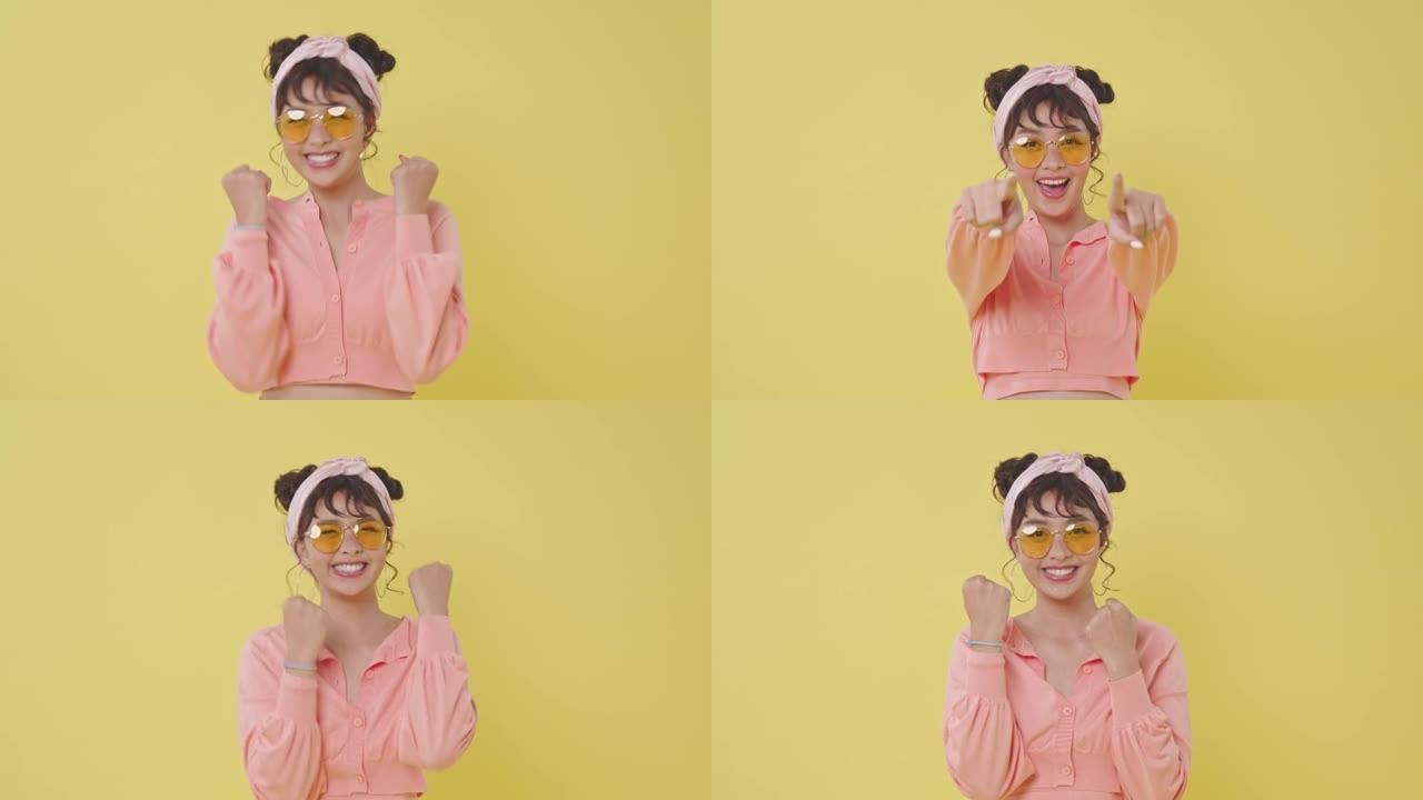快乐的亚洲女孩指着手指孤立在黄色背景上。