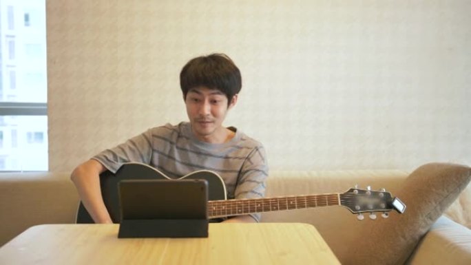 快乐的亚洲男人在家弹吉他