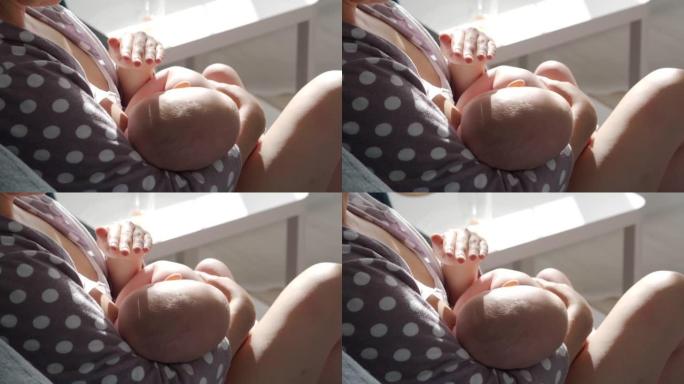 深情的母亲在阳光明媚的客厅里母乳喂养她3个月大的新生男婴，慈爱的母亲用手遮住婴儿的脸。