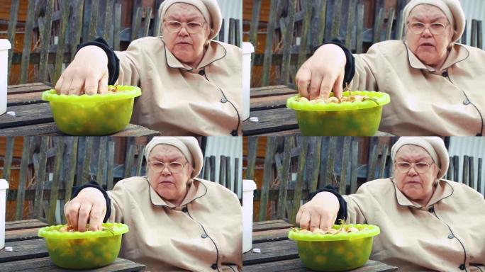 一位老年妇女拆开并检查洋葱幼苗进行种植。