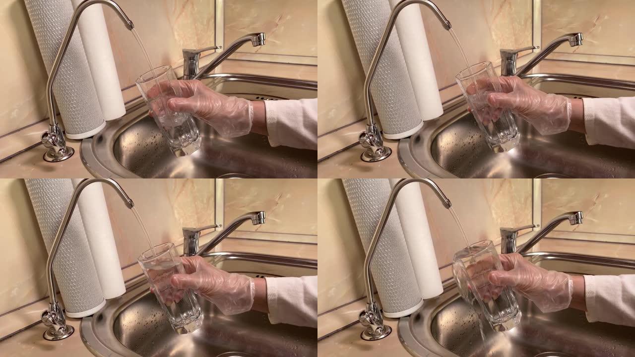 将过滤水从滤水器倒入玻璃中。水槽和水龙头的特写。厨房里的饮用水
