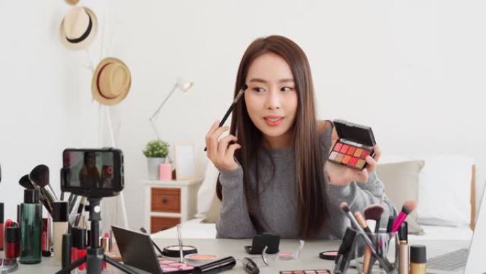 年轻美丽的亚洲女性职业美容影响者在家做化妆教程在线直播