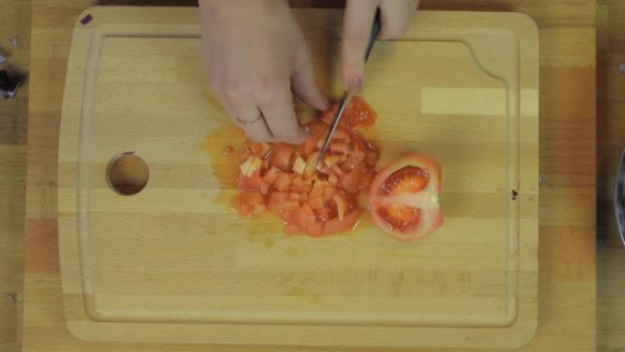 女人在木制厨房桌子上切碎番茄