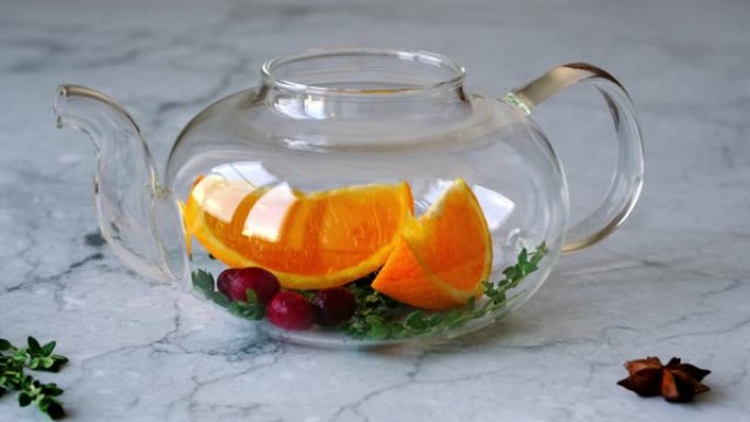 烹饪免疫力提升饮料。玻璃茶壶中的成分: 橙子，蔓越莓和百里香特写