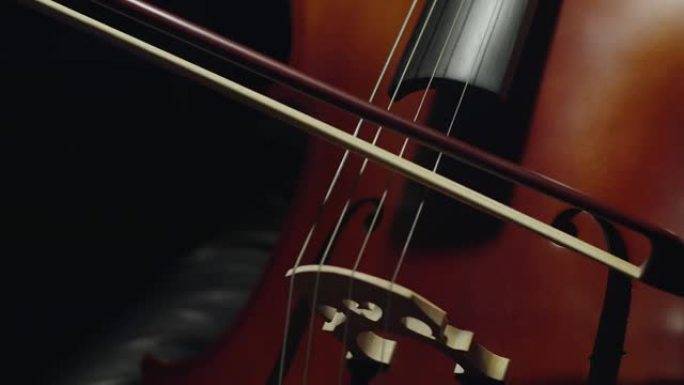 白人妇女演奏大提琴手特写。弓沿着大提琴的琴弦缓慢移动。交响音乐会，演奏乐器