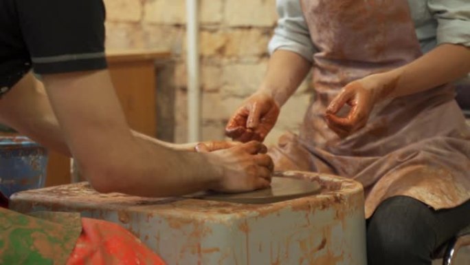 向女人传授制作花盆艺术的男人陶工。在陶工轮上工作的女人