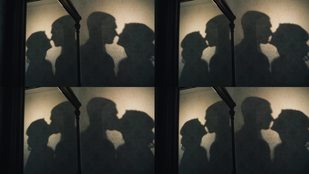 恋人在接吻，他们的影子在房间的墙上可见。有趣的特写镜头