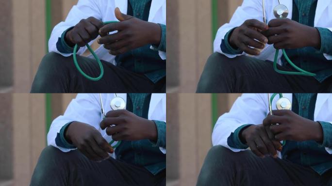 年轻紧张的黑人医生用听诊器休息时的手
