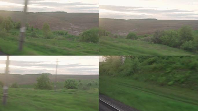 在夏季背景下，从速度列车的窗口观看，玻璃上有眩光，草地和森林的景观上有平行的铁轨。交通、旅行、公路、