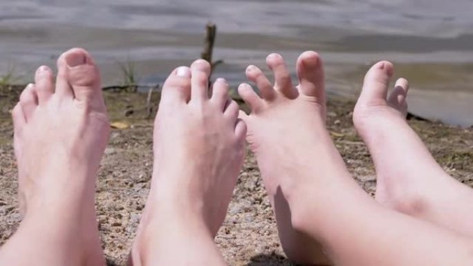 妇女和儿童的脚日光浴在沙滩上的河流，附近的水