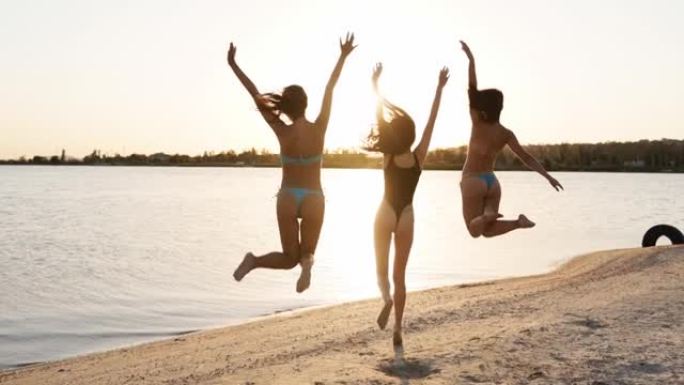 一群快乐的女性朋友在海滩上奔跑和跳入大海或湖水。穿着比基尼的快乐女孩在池塘附近的岸边玩得开心。年轻女