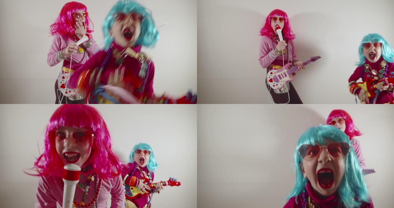 有趣可爱的快乐小女孩播放器吉他和麦克风唱歌，穿着五颜六色的流行套装，如太阳镜和五颜六色的假发