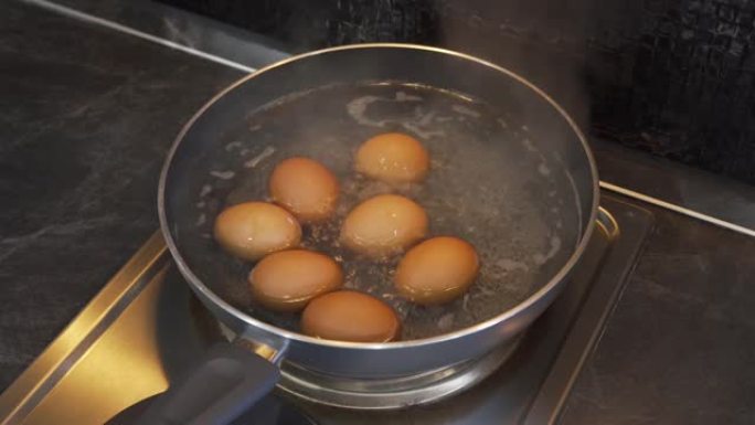 在金属锅中煮鸡蛋，在厨房的电炉上加热。烹饪方法。食物
