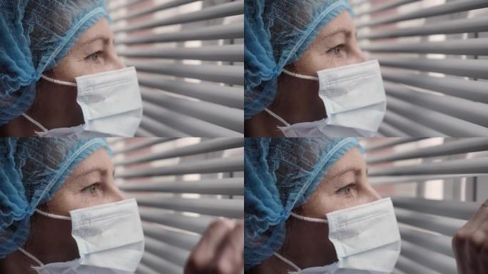 悲伤的病人，过度劳累的严肃的女医护人员看着窗户。肖像医生护士戴着防护口罩，新型冠状病毒肺炎预防传染性