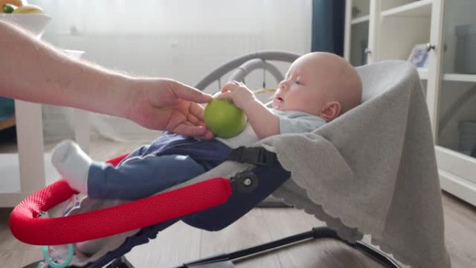 父亲在家和男婴玩耍，刺激婴儿的嗅觉给婴儿介绍不同的香气，父亲给婴儿抱着并闻到水果和蔬菜的味道。