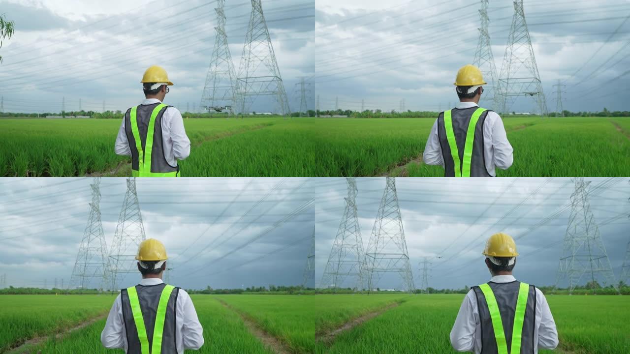 黄色安全帽无人机的电气工程师被用来检查大功率电线杆。位于广阔的草原上