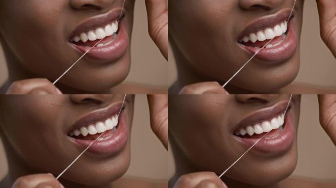 非裔美国妇女在米色背景上使用牙线的特写镜头
