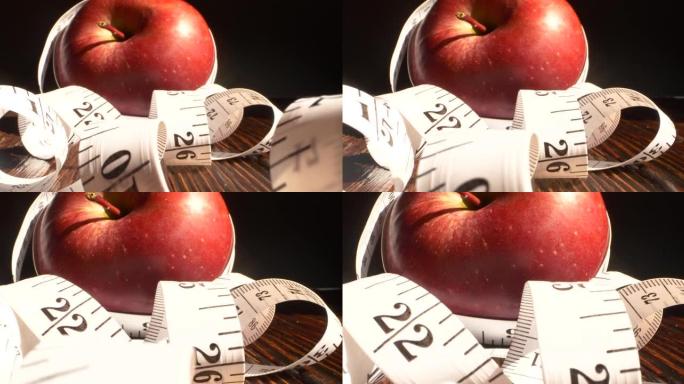 用卷尺包裹的红苹果。饮食，健康饮食，减肥理念