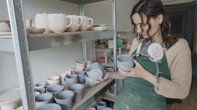 女陶艺家拿着她在工作室制作的盘子