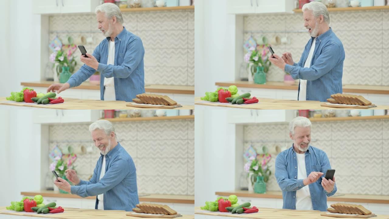 健康的老人在厨房的智能手机上拍摄水果的照片