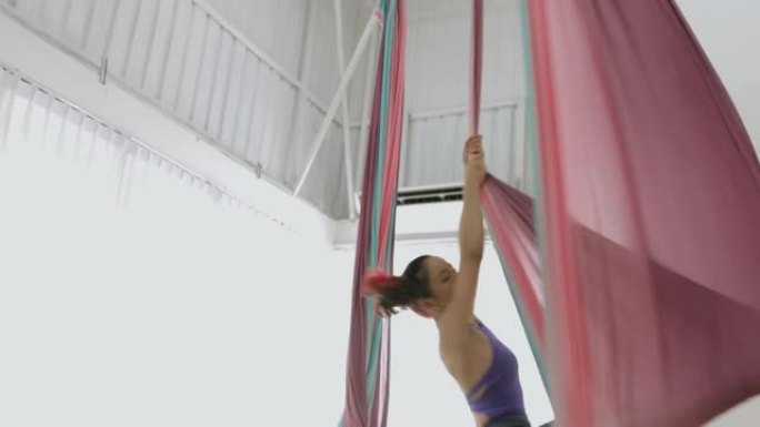 爱好，年轻的空中舞者女人伸开一条腿旋转，用织物吊床活身体-股票视频