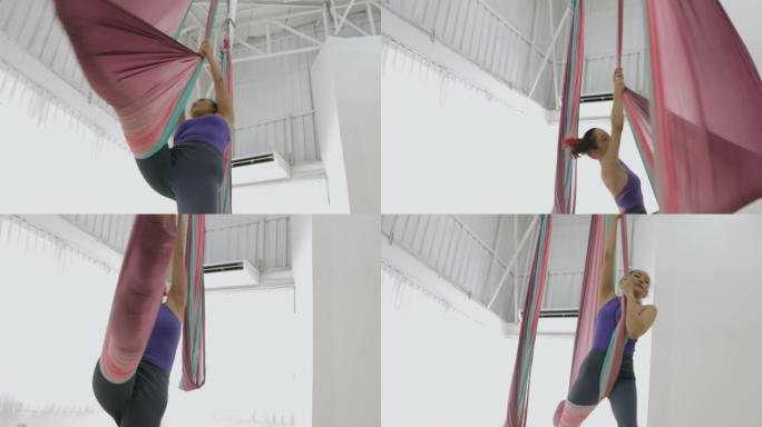 爱好，年轻的空中舞者女人伸开一条腿旋转，用织物吊床活身体-股票视频