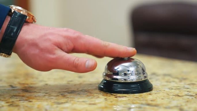 客户接待柜台上的酒店铃声按钮。那个人的手按下了呼叫。酒店接待处打电话给管理员。特写。