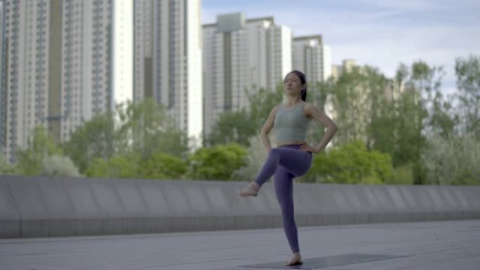 年轻亚洲女子在城市公共广场练习瑜伽