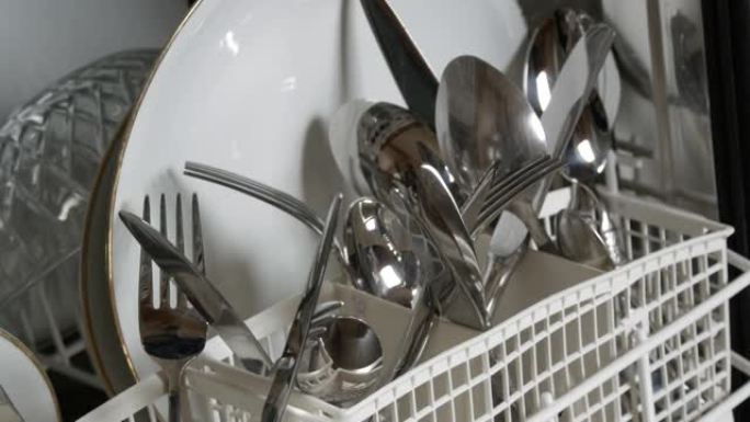 用洗碗机清洗新鲜洗过的盘子。盘子、锅、勺子、叉子、玻璃杯和杯子非常干净