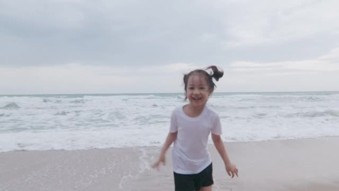 4k可爱的5岁亚洲黑发女孩在海洋海岸附近洋溢着幸福的笑容和享受，看到强烈的海浪和地平线日落，这对孩子