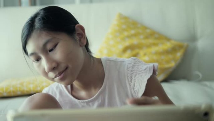 亚洲女孩坐在地板上，在家用数字笔和平板电脑画画，生活方式概念。