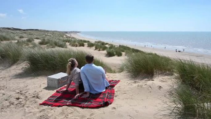 放松的夫妇坐在沙滩毯子上聊天