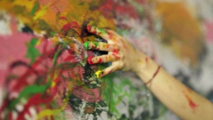 释放你的创造力。年轻女子用手指在画布上涂漆的手的特写，在家庭工作室创作一幅画