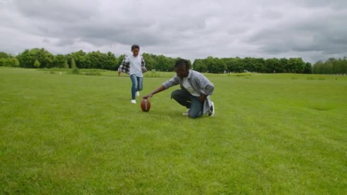 开朗的小美式足球运动员在球场上踢任意球