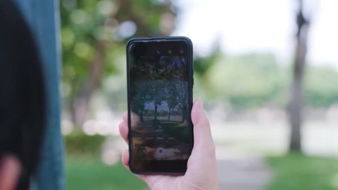 女人使用手机和增强现实应用程序在公园预报天气