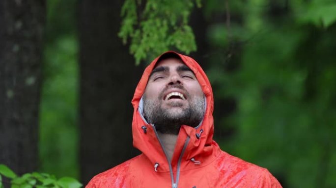 快乐男子在雨中森林徒步旅行，穿着雨衣