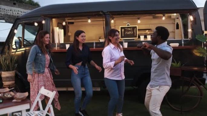 多种族的人在户外餐车前跳舞 -- 多种族的朋友在夏天在外面吃晚餐很开心