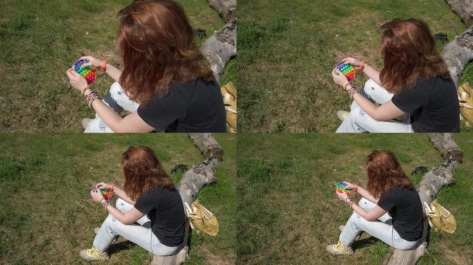 女人坐在草地上玩烦躁玩具，新款时尚硅胶抗压玩具，弹出它和简单的酒窝
