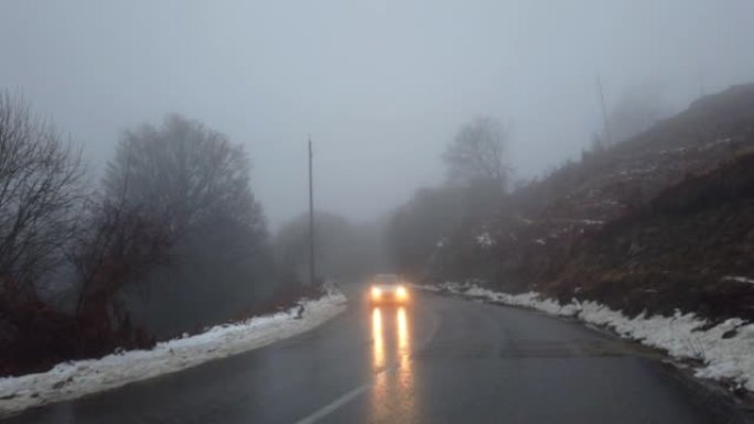 汽车在恶劣天气下在冬季蜿蜒的山路上行驶，有雾且能见度低，危险条件下行驶
