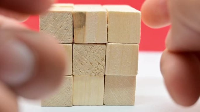 人的手制作一个小方块的木制立方体的近距离延时视频。