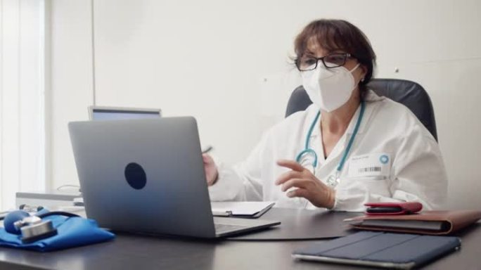 一名女医生在笔记本电脑前挥手