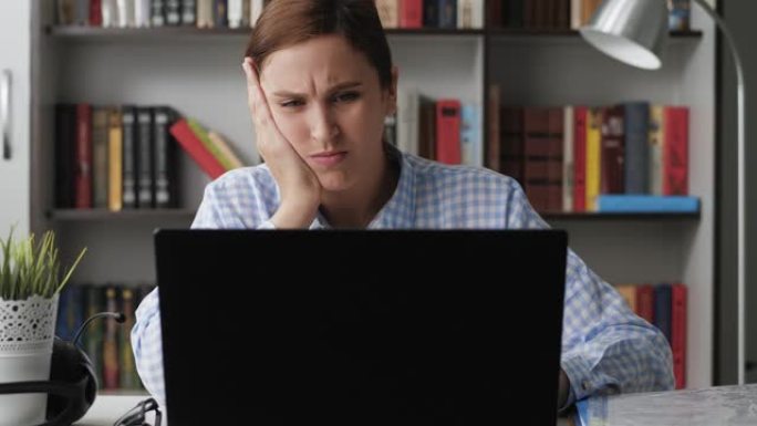 牙痛。工作场所不高兴的女人使用笔记本电脑，她牙痛，用手触摸脸。牙病概念。中镜头视图