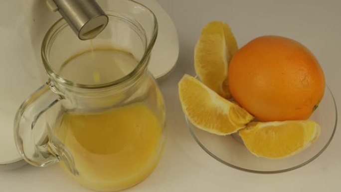 橙汁从榨汁机倒入玻璃壶中