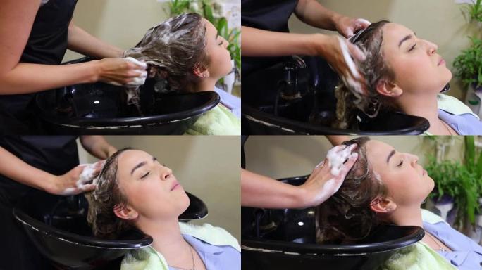 美发师在美发沙龙为一位年轻的年轻女性洗头。