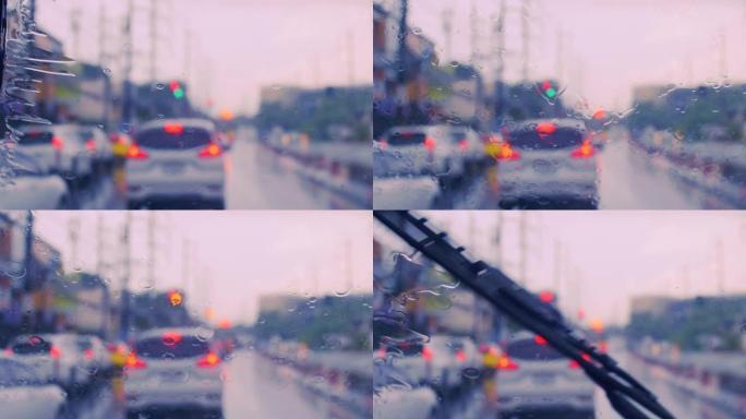 4k驾驶道路上的汽车停在挡风玻璃上的交通信号灯上，雨滴在挡风玻璃上。拍摄挡风玻璃。雨水落在汽车挡风玻
