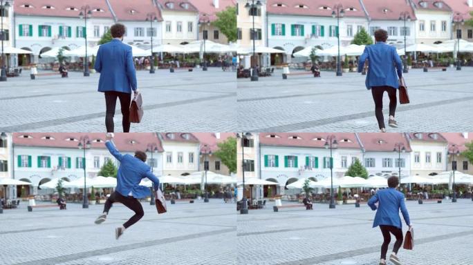 带公文包的聪明休闲男人在中世纪小镇散步，在空中跳跃，在户外庆祝