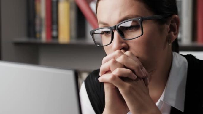 沮丧的女人看着监视器屏幕。工作场所的沉思女人沮丧地看着电脑屏幕。特写