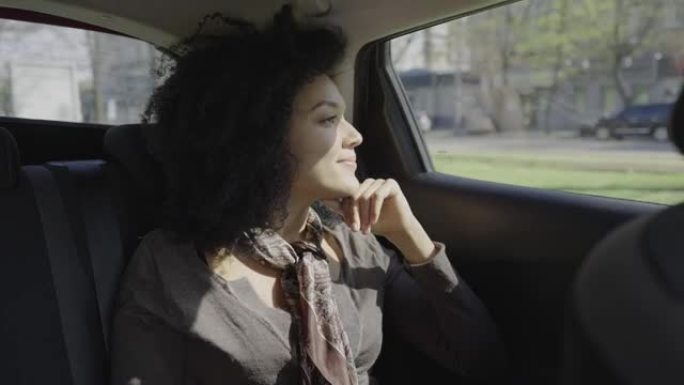 时尚的年轻非洲裔美国妇女的肖像看着窗外，思考着一些事情。混血女性坐在后座的汽车上。特写。慢动作就绪5